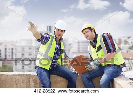 Construction worker and engineer with clipboard pointing at highrise construction site View Large Photo Image Stock Image - Construction worker and engineer with clipboard pointing at highrise construction site. Fotosearch