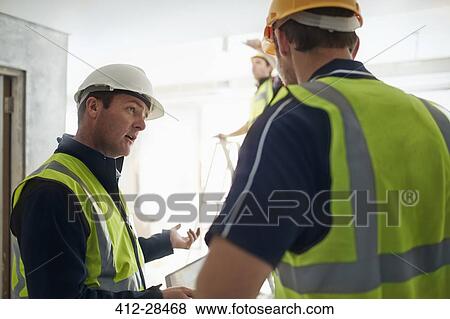 Stock Photo - Construction worker and engineer with digital tablet talking at construction site. Fotosearch