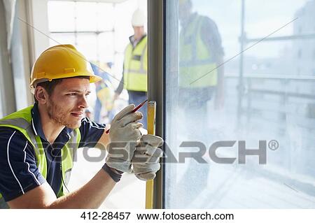 Stock Photo - Construction worker measuring window at construction site. Fotosearch