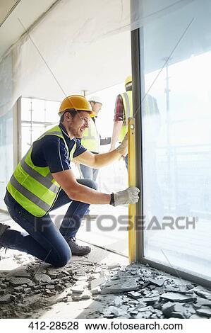 Stock Photo - Construction worker using level tool at construction site. Fotosearch