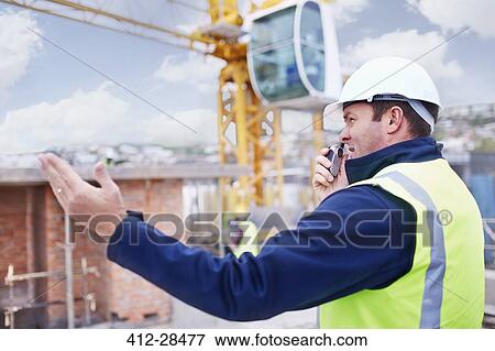 Stock Photo - Construction worker with walkie-talkie at construction site. Fotosearch
