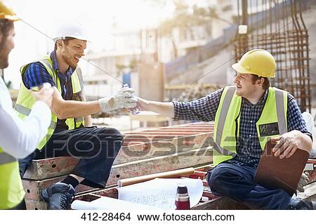 Picture - Construction workers and engineer enjoying coffee break at construction site. Fotosearch