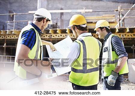 Stock Photography - Construction workers and engineer reviewing blueprints at construction site. Fotosearch