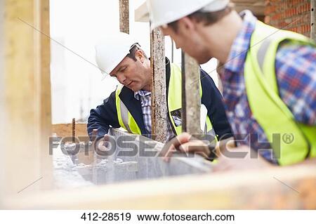 Construction workers examining structure at construction site View Large Photo Image Stock Photo - Construction workers examining structure at construction site. Fotosearch