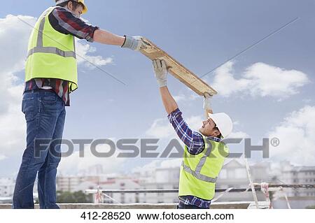 Construction workers lifting part at highrise construction site View Large Photo Image Stock Image - Construction workers lifting part at highrise construction site. Fotosearch