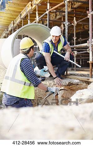 Construction workers talking at construction site View Large Photo Image Stock Photograph - Construction workers talking at construction site. Fotosearch