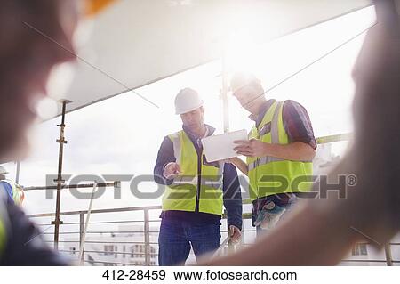 Stock Photo - Construction workers with digital tablet at construction site. Fotosearch