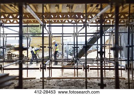 Stock Image - Construction workers working at construction site. Fotosearch
