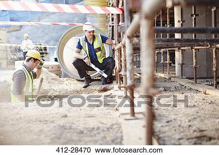 Stock Image - Construction workers working at construction site. Fotosearch