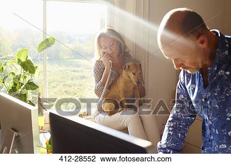 Couple with dog in sunny home office View Large Photo Image Stock Image - Couple with dog in sunny home office. Fotosearch