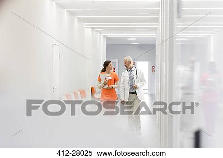 Doctor and nurse making rounds in hospital corridor View Large Photo Image Stock Photography - Doctor and nurse making rounds in hospital corridor. Fotosearch