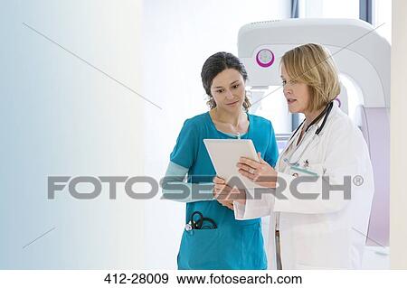 Stock Photo - Doctor and nurse using digital tablet in examination room. Fotosearch