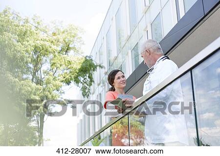 Doctor and nurse with digital tablet talking on hospital balcony View Large Photo Image Stock Photo - Doctor and nurse with digital tablet talking on hospital balcony. Fotosearch