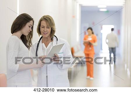 Doctor and patient reviewing medical record in hospital corridor View Large Photo Image Stock Image - Doctor and patient reviewing medical record in hospital corridor. Fotosearch
