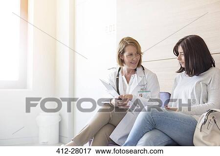 Stock Photo - Doctor and patient reviewing medical record in clinic lobby. Fotosearch