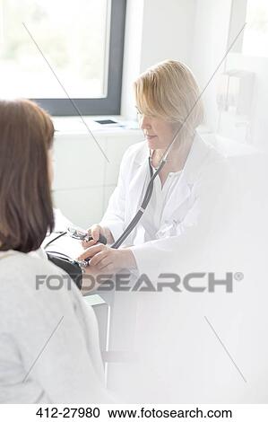 Doctor checking patient’s blood pressure in examination room View Large Photo Image Stock Image - Doctor checking patient’s blood pressure in examination room. Fotosearch