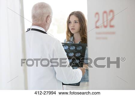 Doctor discussing x-rays with serious teenage patient in examination room View Large Photo Image Picture - Doctor discussing x-rays with serious teenage patient in examination room. Fotosearch