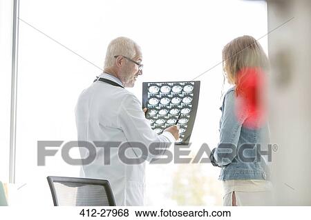 Stock Photo - Doctor reviewing x-rays with patient in doctor’s office. Fotosearch