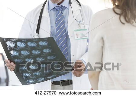 Stock Image - Doctor reviewing x-rays with patient. Fotosearch