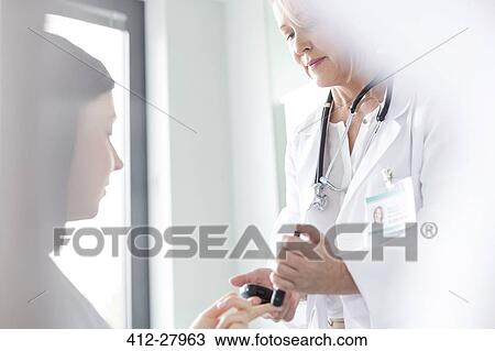 Doctor testing patient blood sugar for diabetes in examination room View Large Photo Image Stock Image - Doctor testing patient blood sugar for diabetes in examination room. Fotosearch
