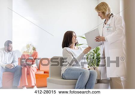 Doctor with clipboard talking to patient in clinic lobby View Large Photo Image Stock Photography - Doctor with clipboard talking to patient in clinic lobby. Fotosearch