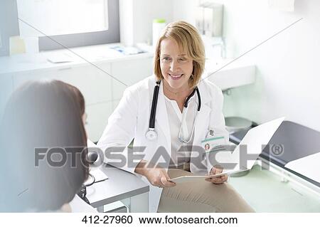 Stock Image - Doctor with medical chart talking with patient in examination room. Fotosearch