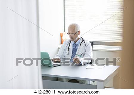 Doctor working at laptop in doctor’s office View Large Photo Image Stock Image - Doctor working at laptop in doctor’s office. Fotosearch