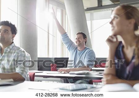 Stock Photo - Eager man raising hand in adult education classroom. Fotosearch