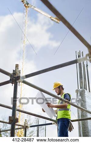 Engineer reviewing blueprints at high rise construction site View Large Photo Image Stock Photo - Engineer reviewing blueprints at high rise construction site. Fotosearch