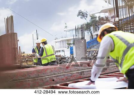 Engineer reviewing blueprints at construction site View Large Photo Image Picture - Engineer reviewing blueprints at construction site. Fotosearch