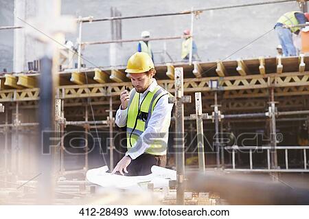 Engineer reviewing blueprints at construction site View Large Photo Image Stock Image - Engineer reviewing blueprints at construction site. Fotosearch