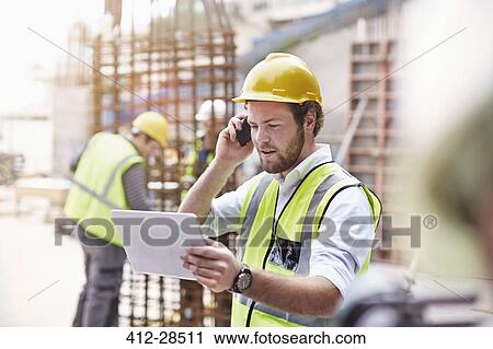 Engineer with digital tablet talking on cell phone at construction site View Large Photo Image Stock Image - Engineer with digital tablet talking on cell phone at construction site. Fotosearch