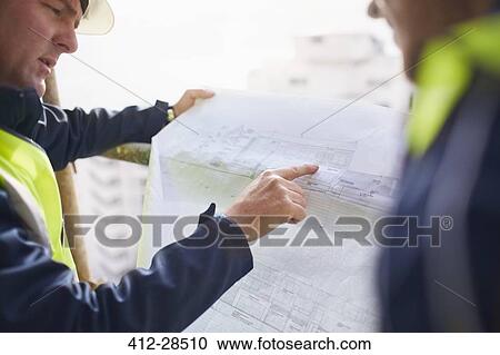 Engineers discussing blueprints at construction site View Large Photo Image Stock Image - Engineers discussing blueprints at construction site. Fotosearch