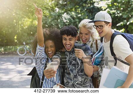 Enthusiastic college students taking selfie in park View Large Photo Image Stock Photo - Enthusiastic college students taking selfie in park. Fotosearch