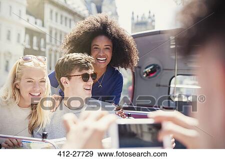 Stock Photo - Enthusiastic friends being photographed on double-decker bus. Fotosearch