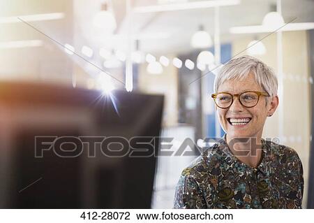 Stock Image - Enthusiastic senior businesswoman looking away in office. Fotosearch