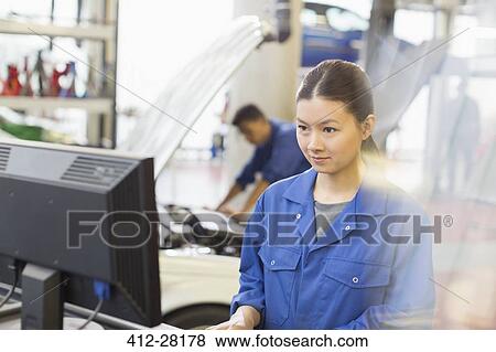 Stock Photo - Female mechanic working at computer in auto repair shop. Fotosearch