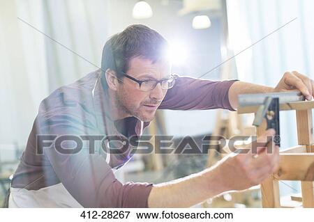 Focused carpenter measuring wood with ruler in workshop View Large Photo Image Stock Photo - Focused carpenter measuring wood with ruler in workshop. Fotosearch