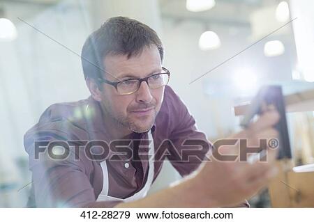 Stock Photo - Focused carpenter working in workshop. Fotosearch