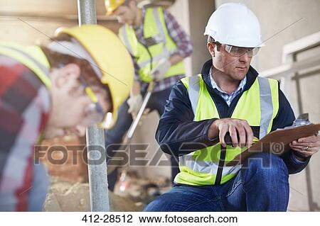 Stock Image - Foreman with clipboard at construction site. Fotosearch