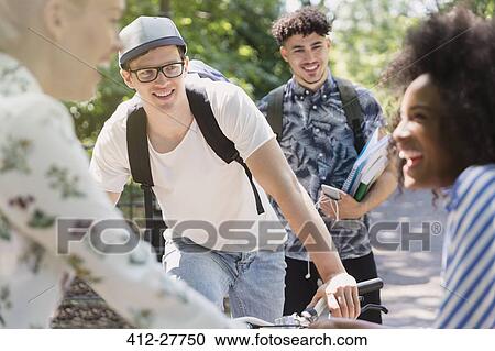Stock Image - Friends hanging out in park. Fotosearch