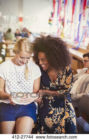 Picture - Friends laughing and drinking cappuccino in cafe. Fotosearch