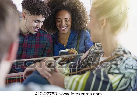 Stock Image - Friends texting with cell phone on bus. Fotosearch