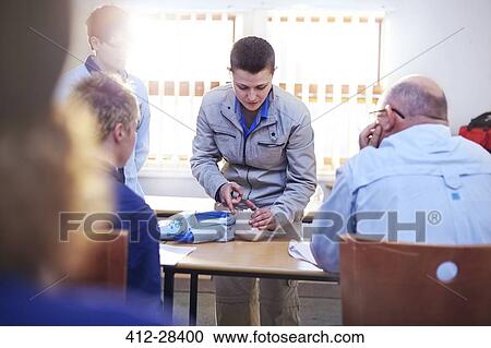 Stock Image - Instructor with CPR dummy teaching first aid class . Fotosearch