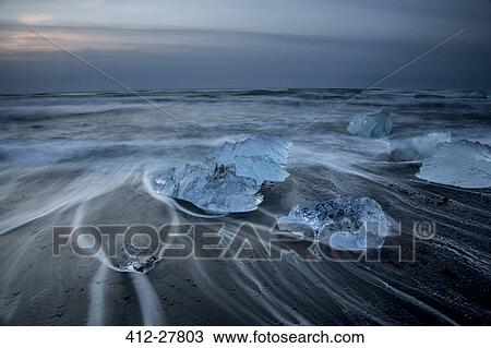 Stock Image - Long exposure of ice on cold stormy ocean beach, Jokulsarlon, Iceland. Fotosearch