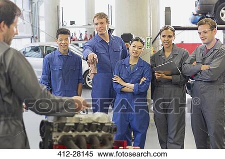 Stock Photography - Mechanic and students discussing car engine in auto repair shop. Fotosearch
