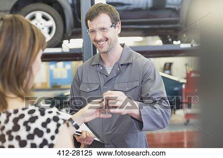 Stock Photography - Mechanic taking keys from woman in auto repair shop. Fotosearch