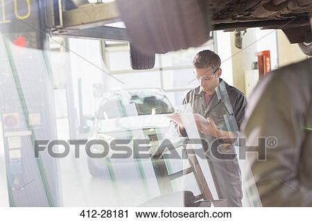 Mechanic with clipboard under car in auto repair shop View Large Photo Image Stock Image - Mechanic with clipboard under car in auto repair shop. Fotosearch