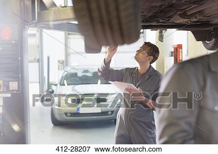 Mechanic with clipboard under car in auto repair shop View Large Photo Image Stock Photo - Mechanic with clipboard under car in auto repair shop. Fotosearch