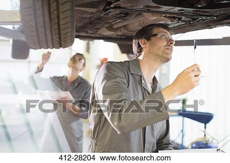 Picture - Mechanic working under car in auto repair shop. Fotosearch